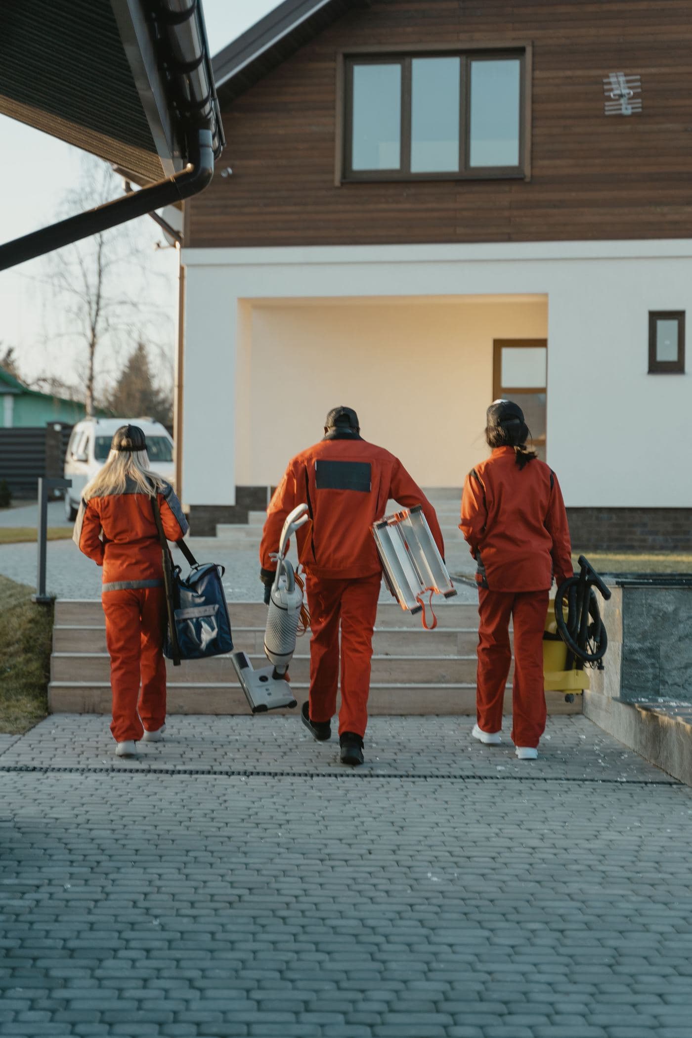 Un equipo de limpieza con uniforme llegando a una casa con sus herramientas