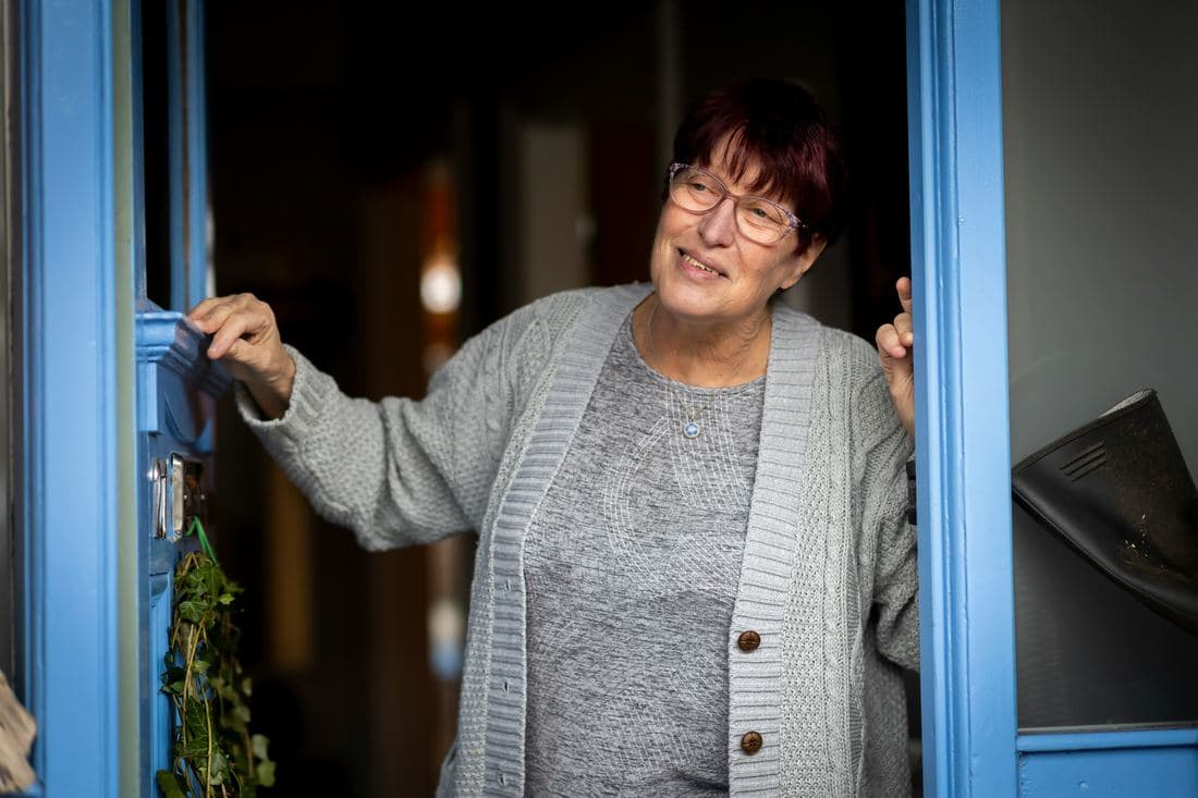 Una clienta sonriente abriendo la puerta de su casa