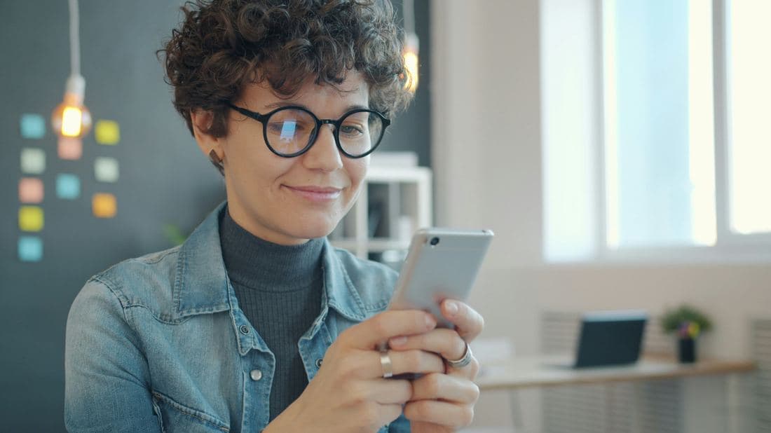 Una clienta sonriente leyendo un texto en su teléfono