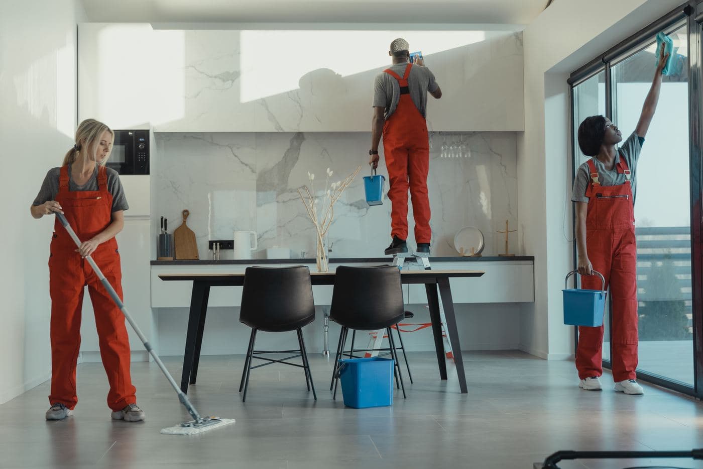 Un equipo de limpieza con uniforme limpiando una cocina y un comedor